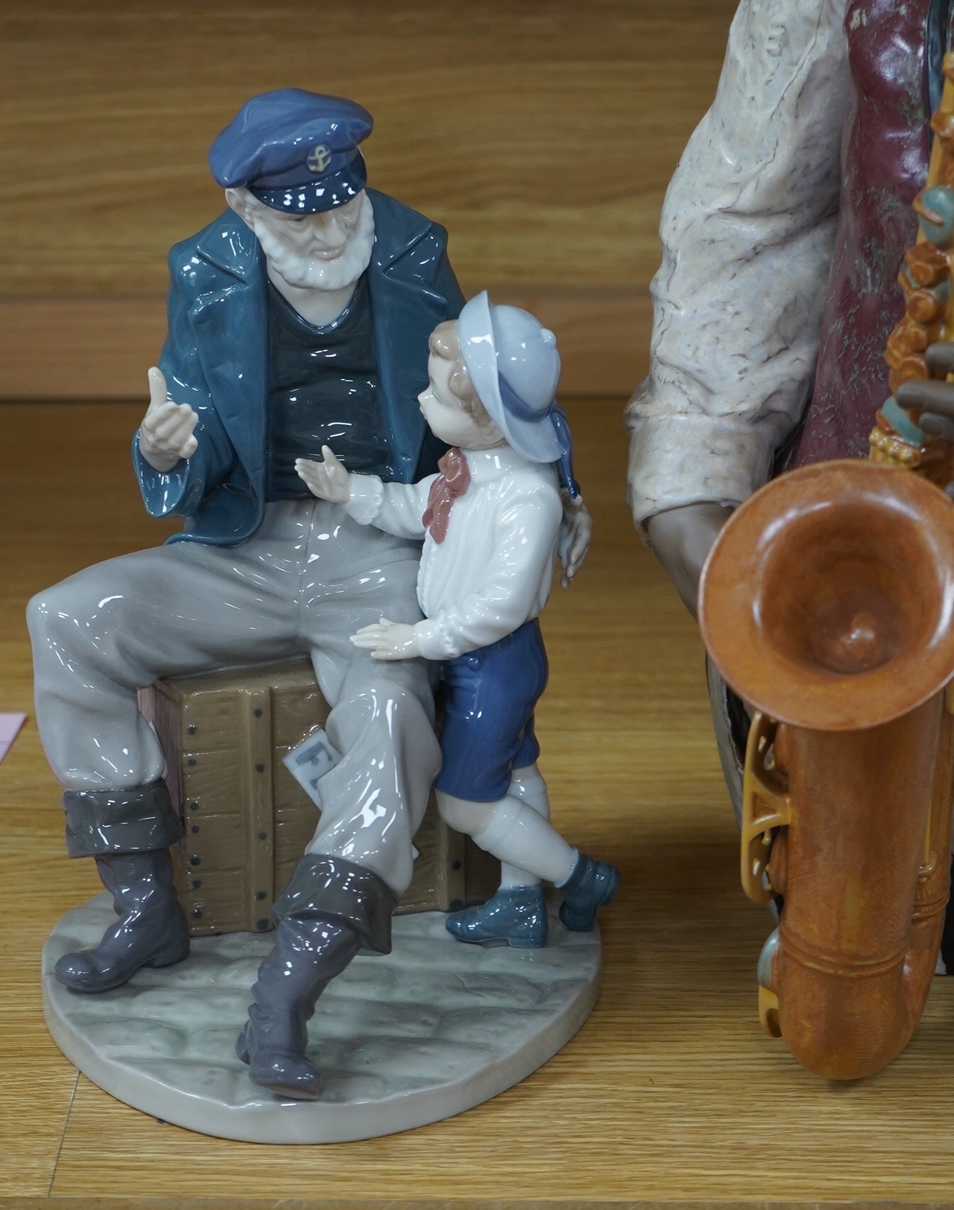 A Lladro figure ‘Playing the Blues’, 63cm high and a ‘Tall Yarn’ figure group of a fisherman and a boy. Condition - fisherman lacking the ship in his hand, otherwise good